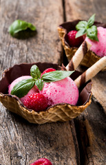 Ice cream, raspberry ice cream scoop in cone on wooden table. 