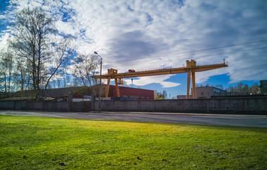 Fototapeta na wymiar Yellow slider crane in closed industrial territory