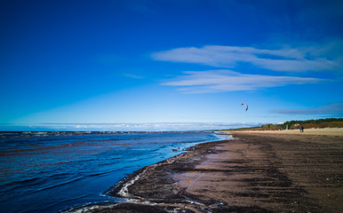 Baltic beach in a sunny cold day with sludge and kite boarder