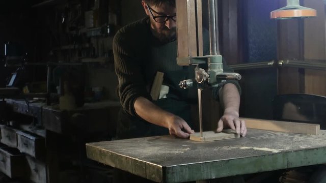 total field on a carpenter who cuts a piece of wood with a band saw