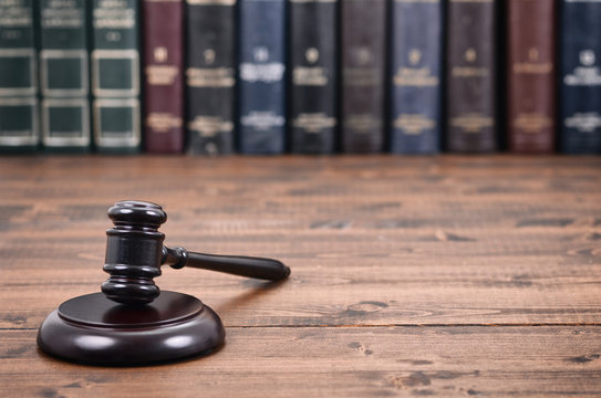  Judge Gavel on a black wooden background in front of law library.