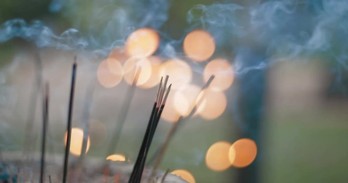 smoldering incense sticks next to a Buddhist temple