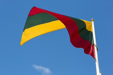 Lithuanian national flag waving on wind against blue cloudy sky