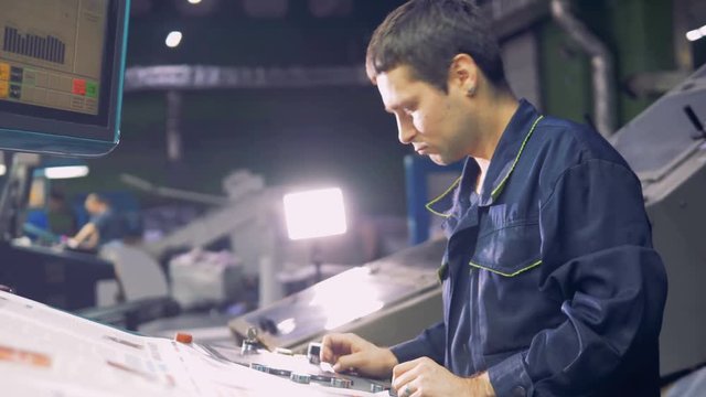 Man working with computerized machine operating with factory line at inductrial plant.