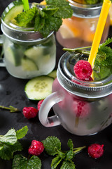 Mohito cucumber, lemon and raspberry drinks on black background. Fresh drinks with fruits on wood. Summer concept.