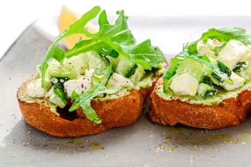 Tasty savory Italian appetizers, or bruschetta, on slices of toasted baguette garnished with basil