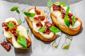 Tasty savory Italian appetizers, or bruschetta, on slices of toasted baguette garnished with basil