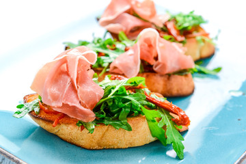 Tasty savory Italian appetizers, or bruschetta, on slices of toasted baguette garnished with basil