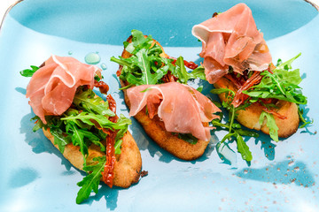 Tasty savory Italian appetizers, or bruschetta, on slices of toasted baguette garnished with basil