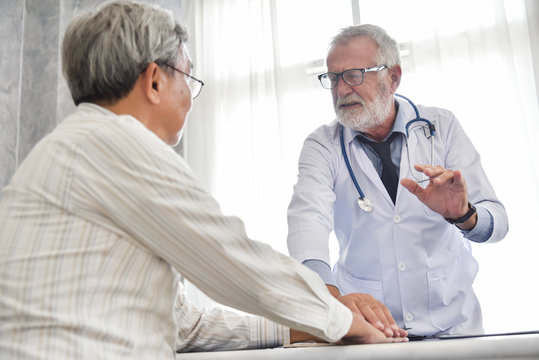 Senior male Doctor is discussing with Asian male patient.
