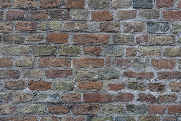 Wall made from red and sometimes colorful bricks of regular shapes and random distribution slotting together precisely. Close up architecture photography. Creative wallpaper photography.