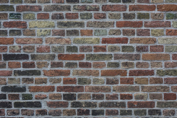 Wall made from red and sometimes colorful bricks of regular shapes and random distribution slotting together precisely. Close up architecture photography. Creative wallpaper photography.