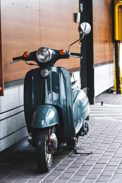 vintage motor scooter parked in front of a building wall
