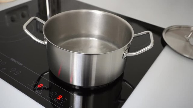 kochendes Wasser im Edelstahltopf auf Induktionsherd