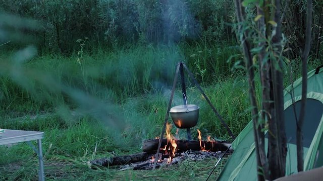 A bonfire in the clearing A bonfire with a bowler on the tripod between the table and the tent in general