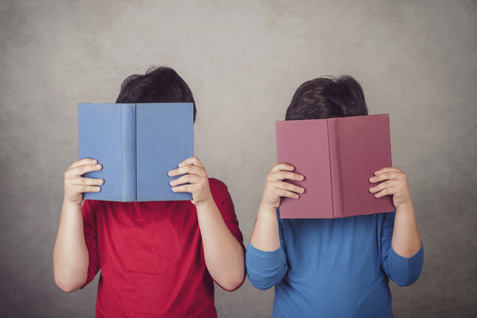 ni&ntilde;os leyendo un libro sobre fondo gris