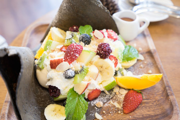 Black crape cake with wipcram topping with fruit berry, banana and orange.