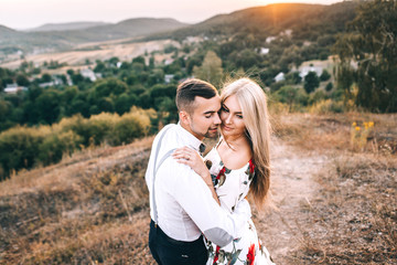 A loving couple hugs and kisses against the backdrop of the mountains at sunset. A gentle kiss