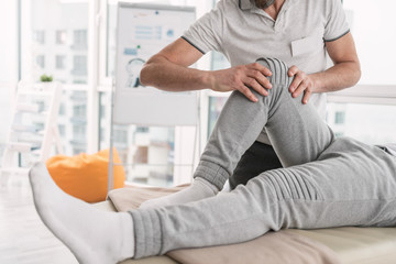 Fototapeta premium Physical trauma. Close up of a male leg being bend during the rehabilitation therapy procedure