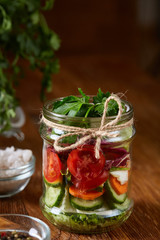 Fresh vegetable salad and ripe veggies on cutting board over wooden background, close up, selective focus