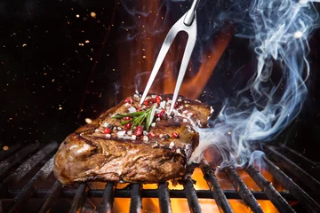 Crédence de cuisine en verre imprimé Grill / Barbecue Steak de boeuf sur le gril avec des flammes