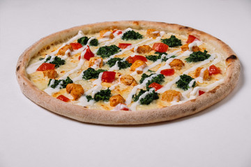 Pizza with chicken, tomato and spinach on white.