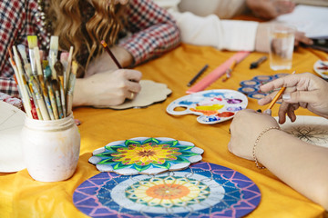 Women's hands, brushes and paints close-up draw on artistic training to create the mandala of life
