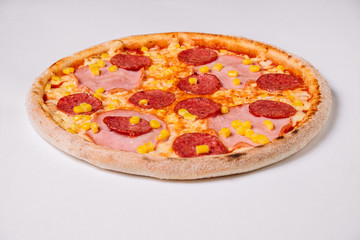 Pizza with salami, ham and corn isolated on white