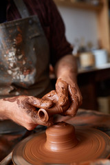 Portrait of a male potter in apron molds bowl from clay, selective focus, close-up