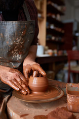 Portrait of a male potter in apron molds bowl from clay, selective focus, close-up