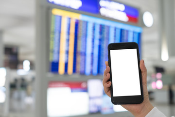 A woman hand holding smart phone device in the airport schedule flight background.