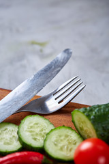 Fresh vegetable salad and ripe veggies on cutting board over white background, close up, selective focus