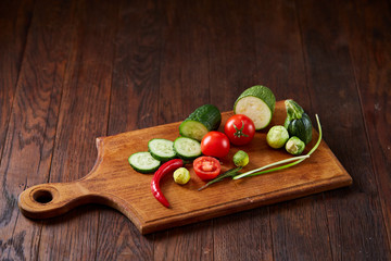 Fresh vegetable salad and ripe veggies on cutting board over white background, close up, selective focus