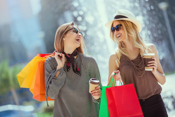 Happy friends shopping. Young friends enjoying shopping in the city, holding shopping bags and coffee to go