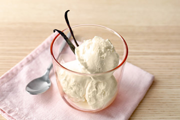 Glass with tasty vanilla ice cream on wooden background