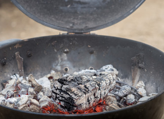 Hot charcoal burns in the grill with embers