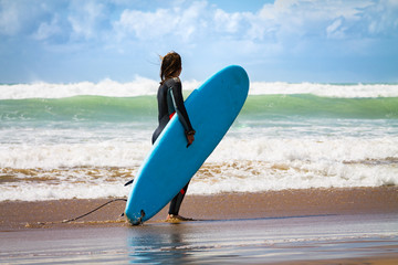 A surfer with a surfboard is walking along the beach. Atlantic Ocean. Photo travel. Leisure....
