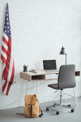 interior of modern living room with american flag on brick wall and table with laptop