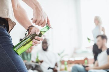 cropped image of man opening beer bottle by corkscrew
