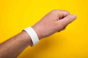 Fototapeta premium White wristband, bracelet mockup for event on yellow background.