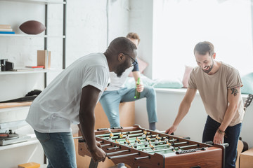 two young multiethnic friends playing table football