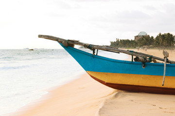 Naklejka na ściany i meble Close-up Sri-Lanka fishing boat on the ocean Narigama beach. Traditional blue-yellow wooden painted ship.