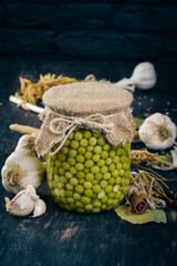 Pickled green peas in a jar. Stocks of food. Top view. On a wooden background. Copy space.