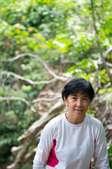 Asian senior woman hiking through the rain forest