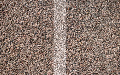 A faded white stripe on the asphalt in the evening light. View from above.
