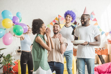 Happy young men and woman celebrating with birthday cake  on surprise party