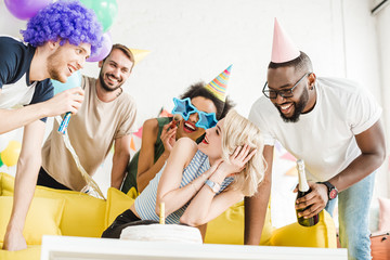 Obraz premium Cheerful friends greeting blonde woman with birthday cake