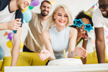 Young multiracial people celebrating with birthday cake