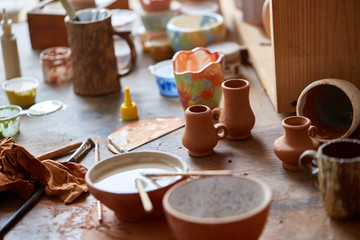 Close-up of various paint mugs and brushes in holder on worktop, selective focus, side view.