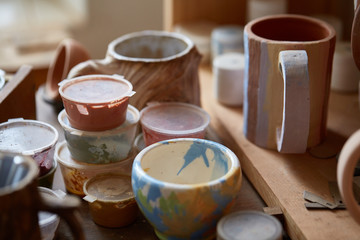 Close-up of various paint mugs and brushes in holder on worktop, selective focus, side view.
